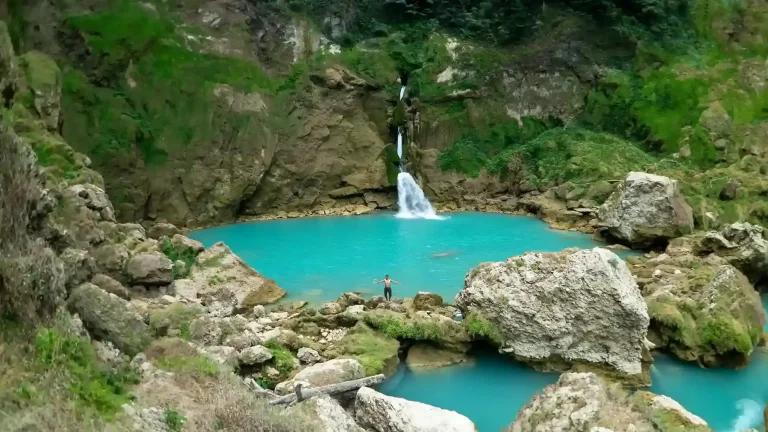 Matayangu Waterfall spilling into a turquoise pool among mossy boulders in Sumba
